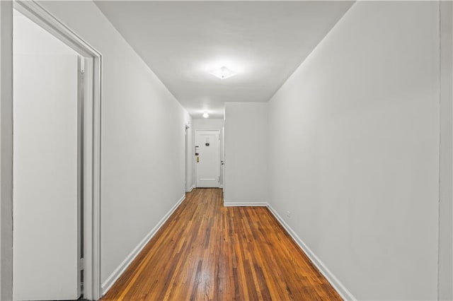 corridor featuring wood-type flooring and baseboards