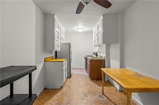 kitchen with white cabinets, ceiling fan, freestanding refrigerator, baseboards, and gas range