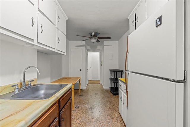 kitchen with freestanding refrigerator, a ceiling fan, light countertops, white cabinets, and a sink