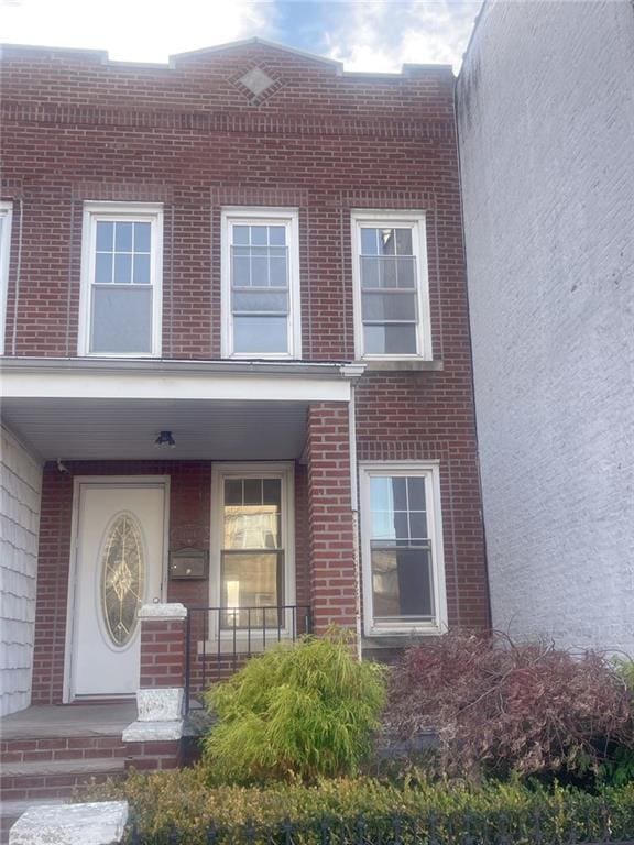 doorway to property with brick siding and a porch