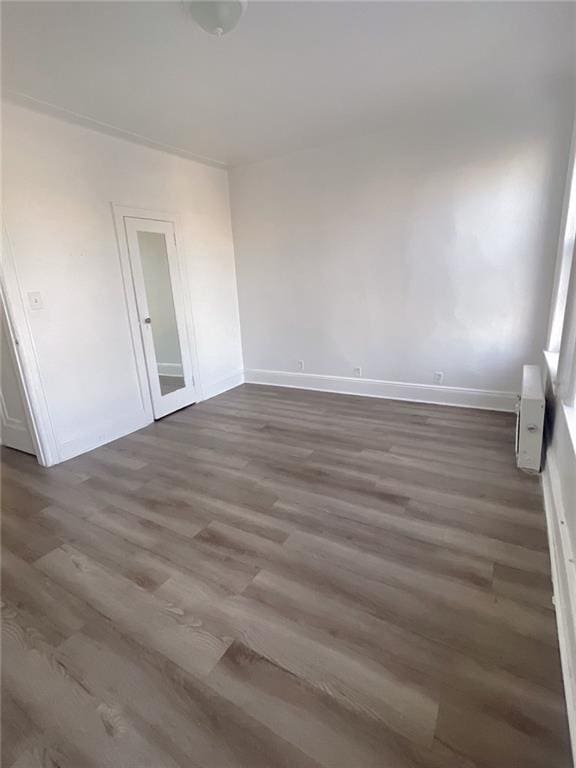 spare room with baseboards and wood finished floors