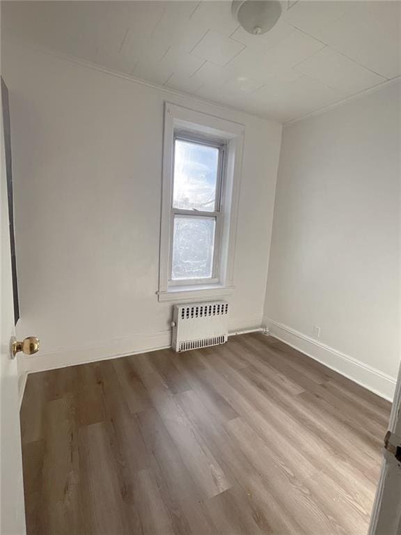 spare room featuring radiator heating unit, wood finished floors, and baseboards