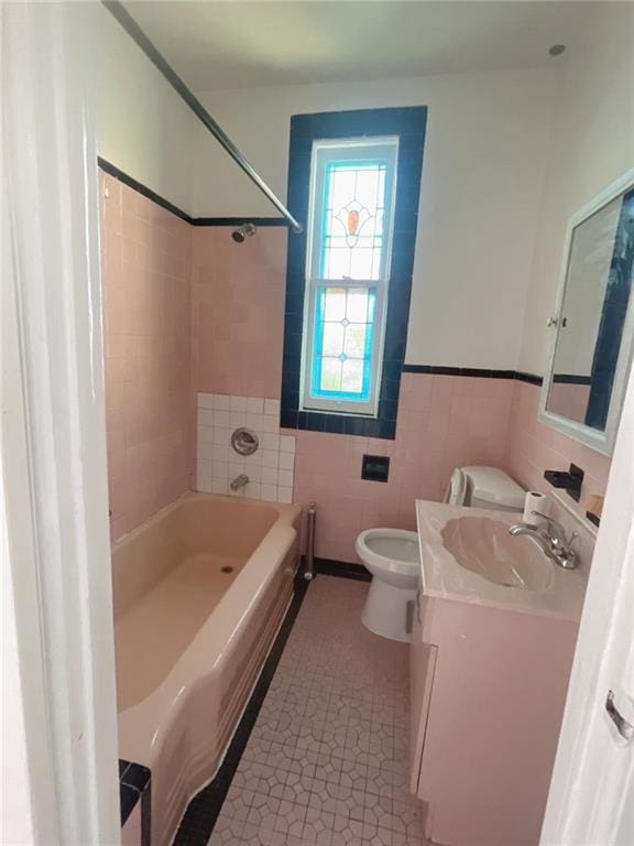 bathroom with vanity, shower / bathing tub combination, tile patterned flooring, tile walls, and toilet