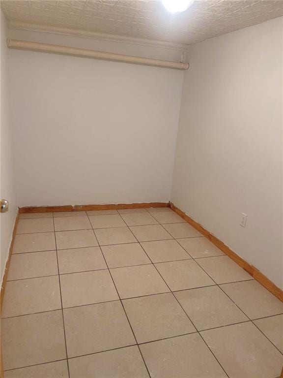 empty room featuring light tile patterned floors, a textured ceiling, and baseboards