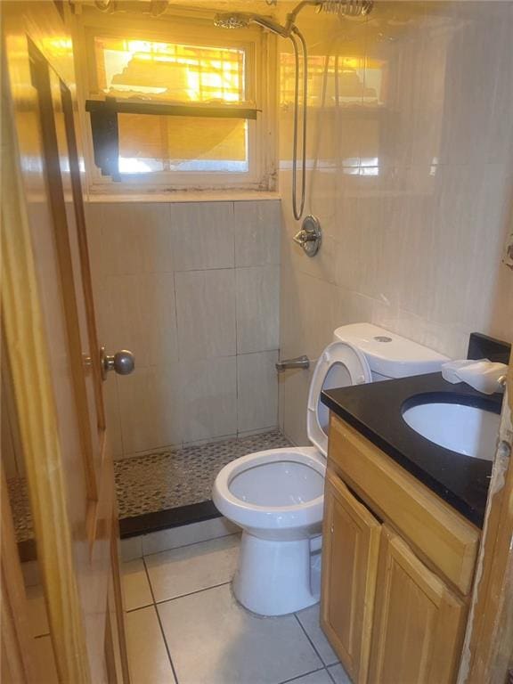 bathroom featuring vanity, a stall shower, tile walls, toilet, and tile patterned floors