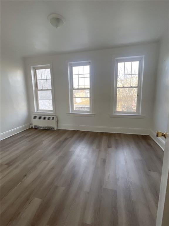 empty room featuring radiator, baseboards, and wood finished floors