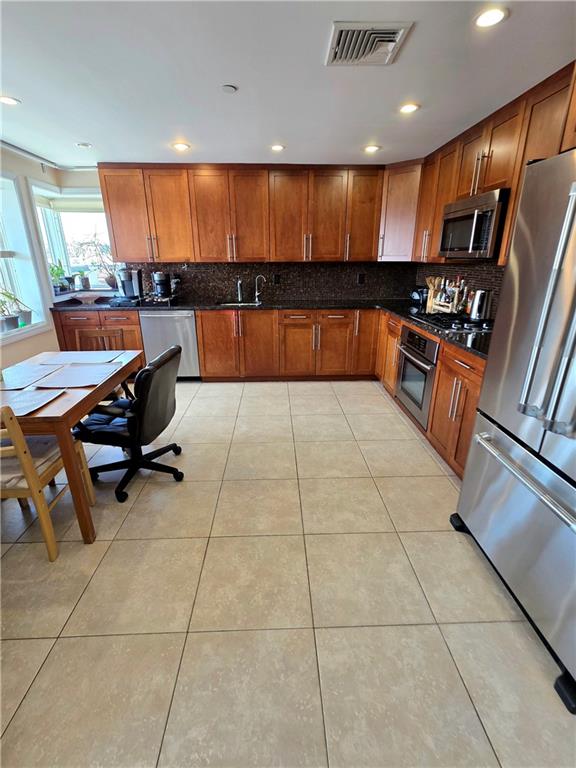 1927 78th St Unit 4A, Brooklyn, NY 11214 - kitchen featuring stainless steel appliances, decorative backsplash, brown cabinetry, recessed lighting, and light tile patterned floors