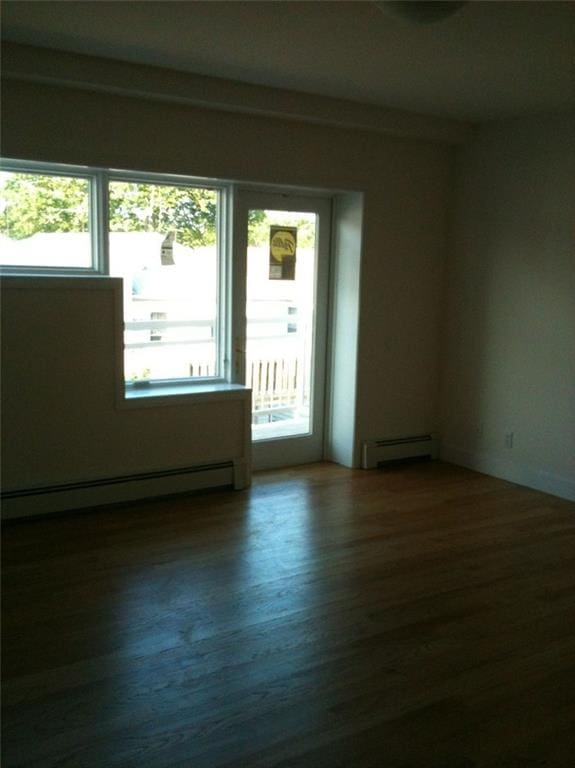 empty room with baseboard heating and dark wood-style flooring