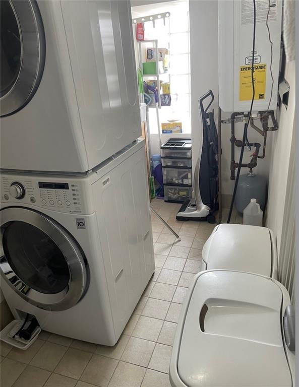 laundry area with tankless water heater, laundry area, stacked washing maching and dryer, and light tile patterned floors