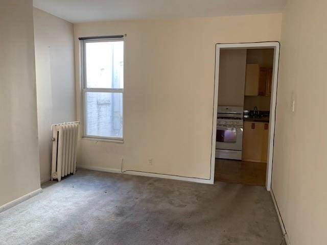 carpeted spare room with radiator and sink