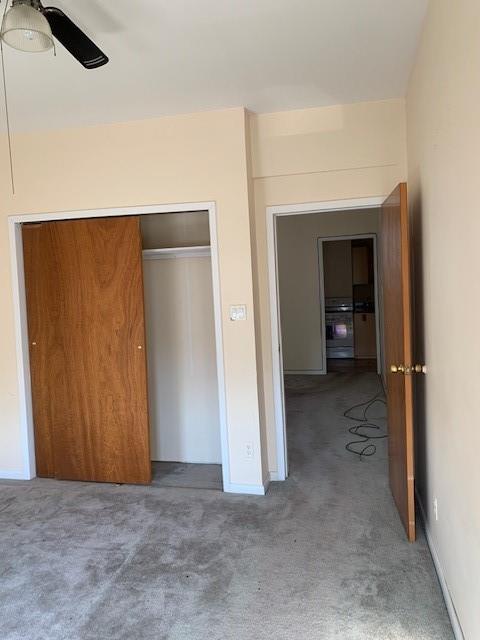 unfurnished bedroom with ceiling fan, carpet flooring, and a closet