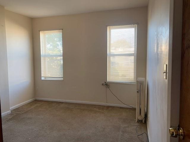 carpeted empty room featuring radiator heating unit