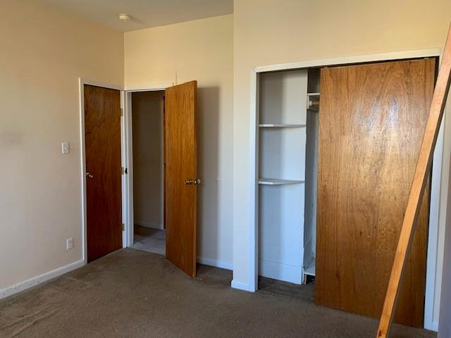 unfurnished bedroom featuring a closet and dark colored carpet