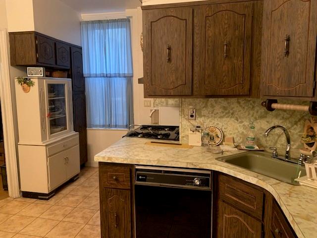 kitchen featuring tasteful backsplash, sink, dark brown cabinets, and black appliances