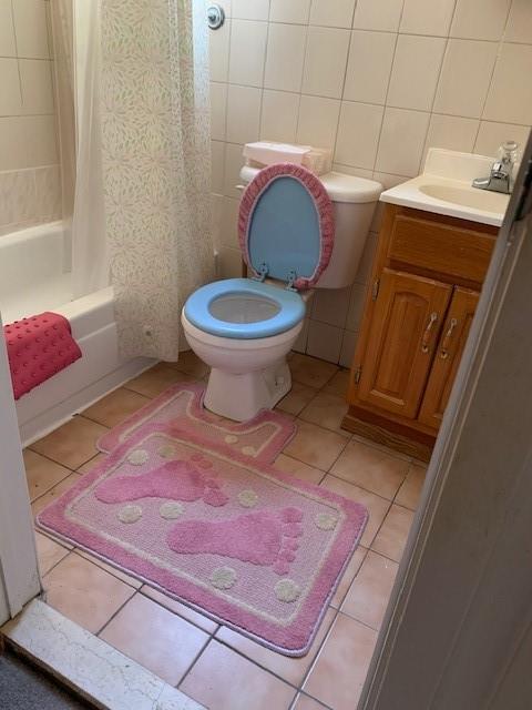 full bathroom with tile walls, shower / tub combo, vanity, decorative backsplash, and toilet