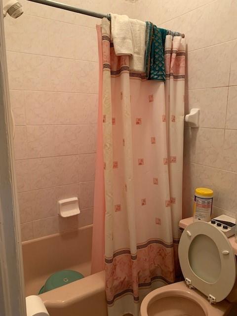 bathroom featuring toilet and shower / bathtub combination with curtain