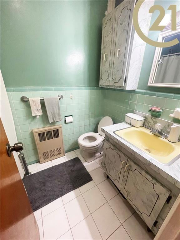 bathroom featuring vanity, radiator, tile patterned floors, toilet, and tile walls