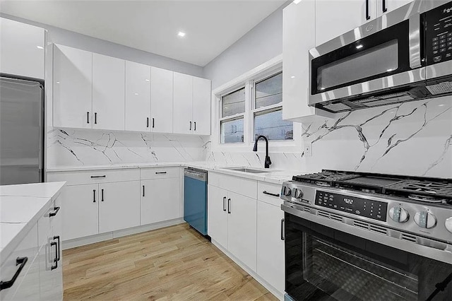 kitchen with sink, tasteful backsplash, light hardwood / wood-style floors, white cabinetry, and stainless steel appliances