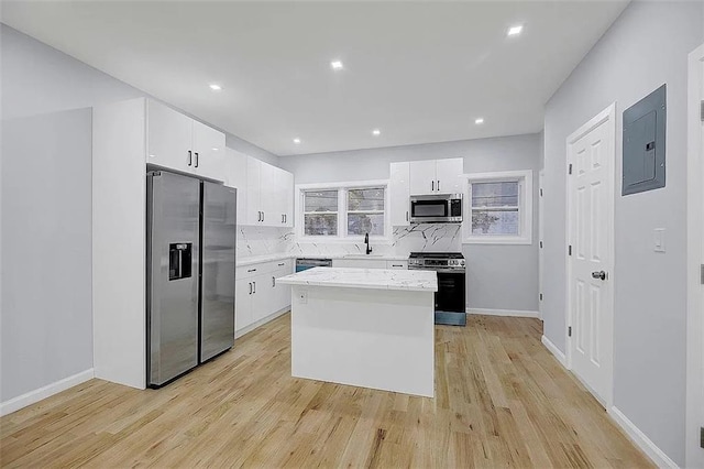 kitchen featuring electric panel, white cabinetry, a center island, and appliances with stainless steel finishes