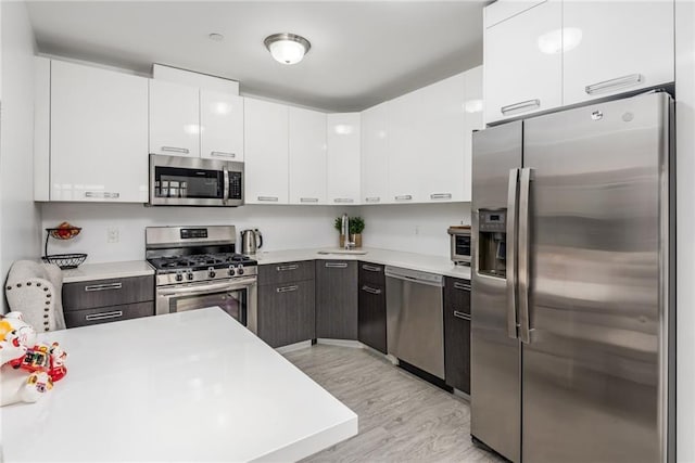 kitchen with white cabinets, stainless steel appliances, and light hardwood / wood-style flooring