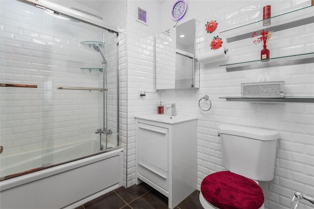 bathroom with combined bath / shower with glass door, backsplash, tile patterned floors, and toilet