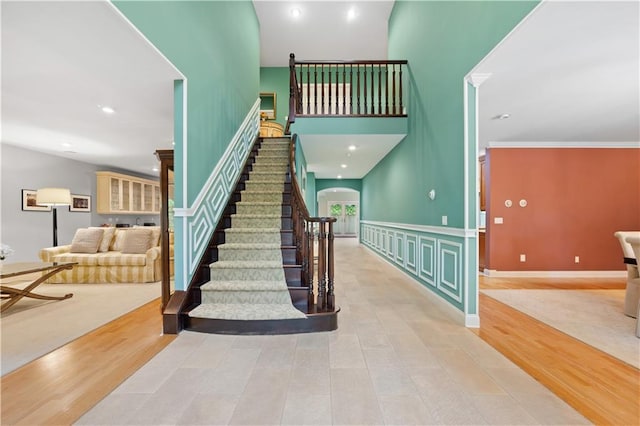 stairway featuring hardwood / wood-style floors, a towering ceiling, and crown molding