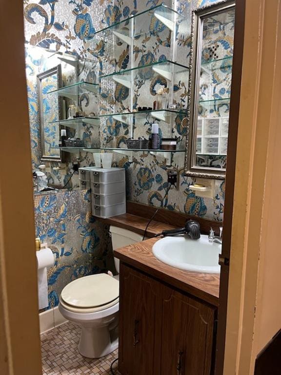 bathroom featuring vanity, toilet, and wallpapered walls