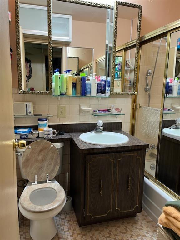 bathroom featuring enclosed tub / shower combo, backsplash, vanity, and tile patterned floors