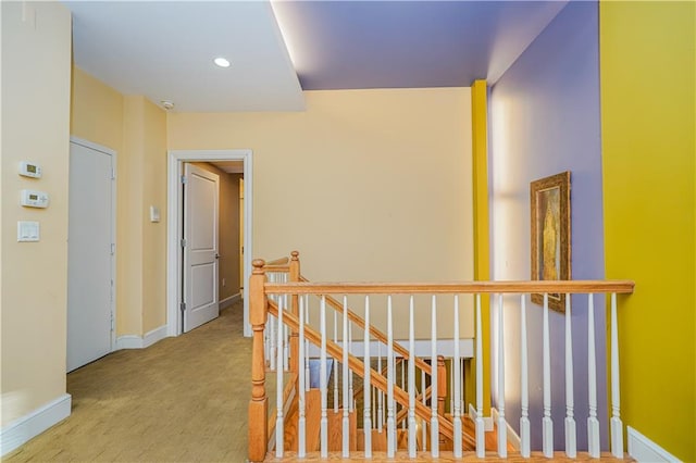 hall with recessed lighting, an upstairs landing, and baseboards