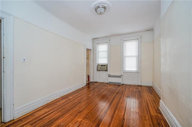 spare room with radiator, dark wood-style floors, baseboards, and cooling unit