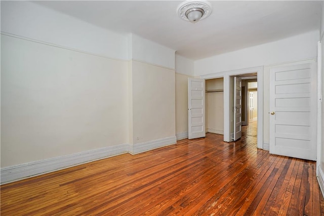 unfurnished bedroom with a closet, wood-type flooring, and baseboards