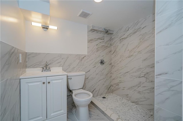 bathroom featuring toilet, vanity, visible vents, marble finish floor, and tiled shower