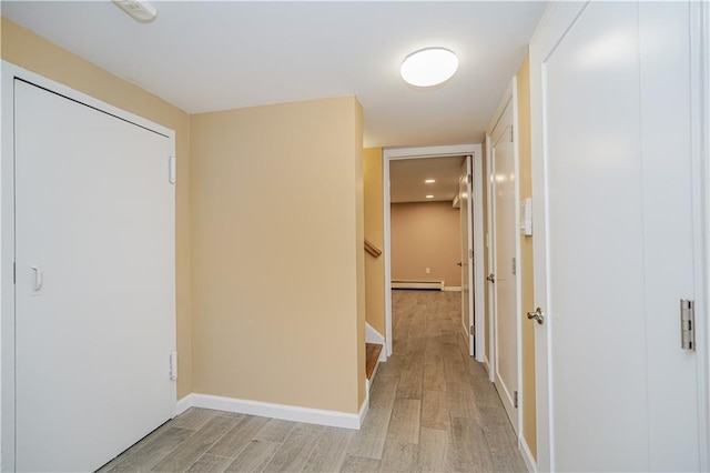 hall featuring baseboards, light wood-style flooring, and baseboard heating