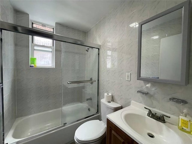 full bathroom featuring tasteful backsplash, bath / shower combo with glass door, vanity, tile walls, and toilet