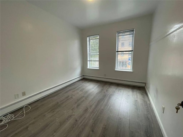 empty room featuring a baseboard radiator and dark hardwood / wood-style floors