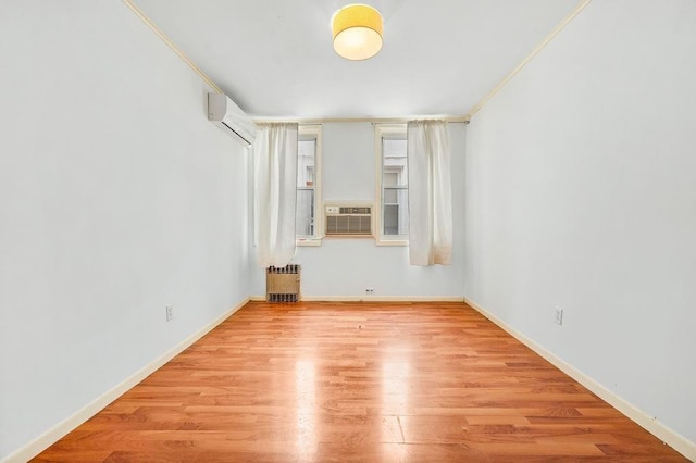 unfurnished room featuring radiator, baseboards, a wall mounted air conditioner, cooling unit, and wood finished floors