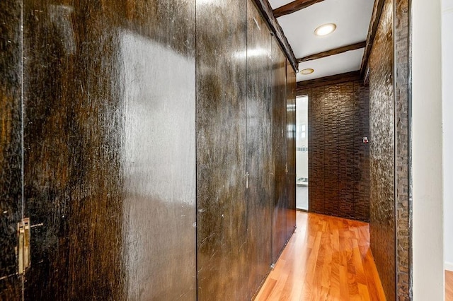 hall with light hardwood / wood-style floors and beamed ceiling