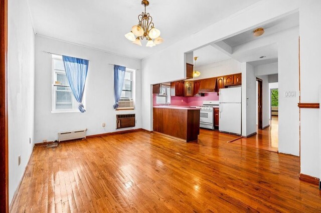 kitchen featuring an inviting chandelier, baseboard heating, pendant lighting, white appliances, and hardwood / wood-style floors