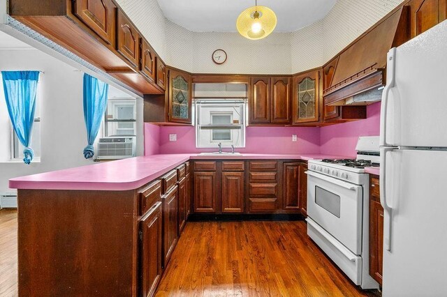 kitchen featuring white appliances, custom range hood, kitchen peninsula, and hanging light fixtures