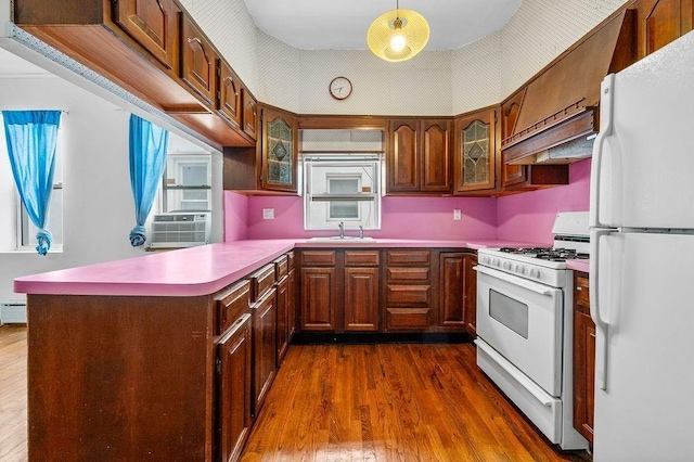 kitchen with under cabinet range hood, a baseboard heating unit, dark wood finished floors, white appliances, and a peninsula