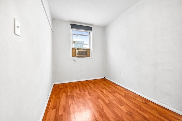 spare room with cooling unit, wood finished floors, and baseboards