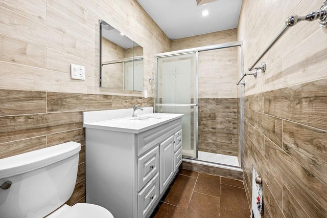 full bath with tile patterned floors, toilet, a stall shower, tile walls, and vanity