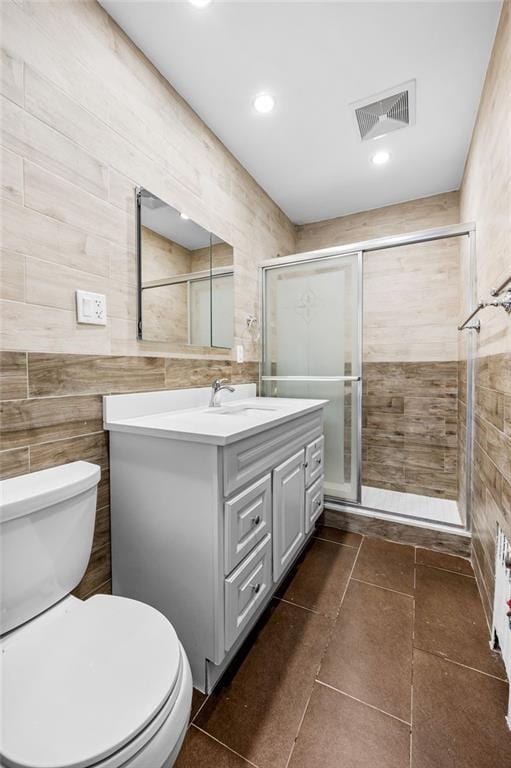 full bathroom with vanity, visible vents, a shower stall, tile walls, and toilet