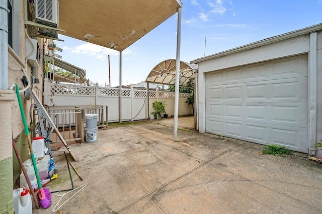 view of patio / terrace featuring a garage, an outbuilding, driveway, and fence