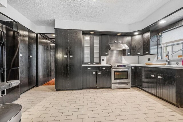 kitchen with sink, stainless steel range with electric stovetop, a textured ceiling, black fridge, and exhaust hood