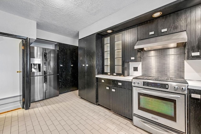 kitchen featuring under cabinet range hood, light countertops, decorative backsplash, appliances with stainless steel finishes, and a textured ceiling