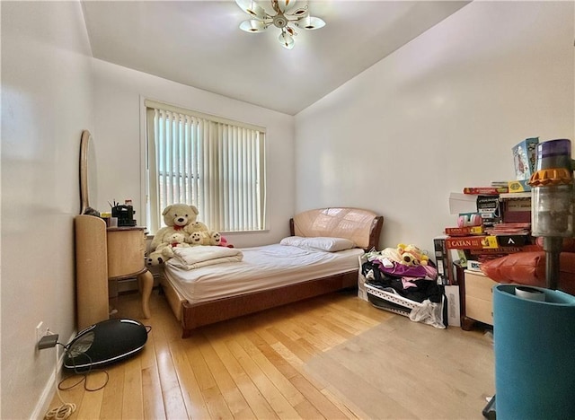 bedroom with a notable chandelier, baseboards, vaulted ceiling, and hardwood / wood-style floors