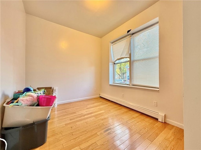 living area with a baseboard radiator, wood-type flooring, and baseboards