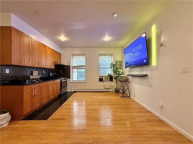 kitchen with tasteful backsplash, brown cabinetry, gas range, wood finished floors, and baseboards