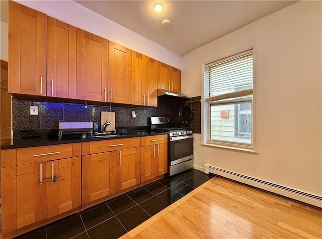 kitchen with stainless steel range with gas stovetop, a sink, backsplash, and baseboard heating